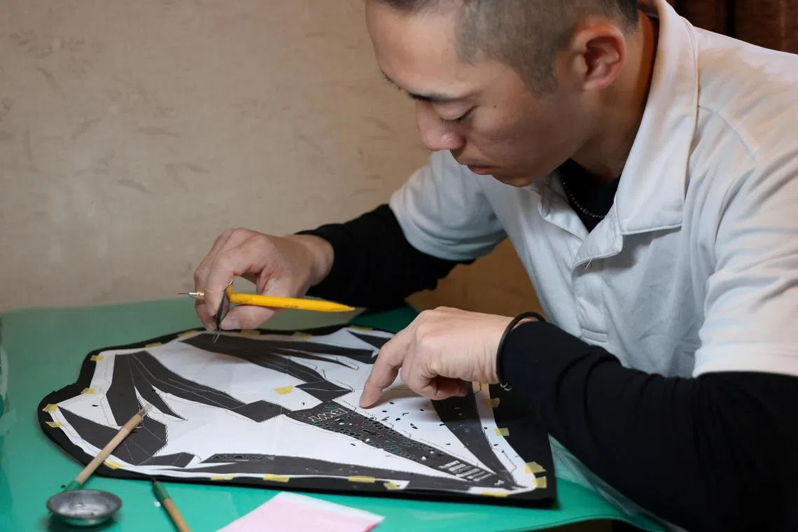Kenji Tanaka works to produce a Formula One paper model with the traditional craft Ise Katagami in Suzuka, Japan March 27, 2024. REUTERS/Irene Wang