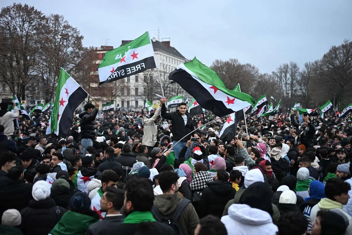 Members of the Syrian community wave Syrian flags as they attend a rally on December 8, 2024 in Berlin, Germany, to celebrate the end of Syrian dictator Bashar al-Assad's rule.