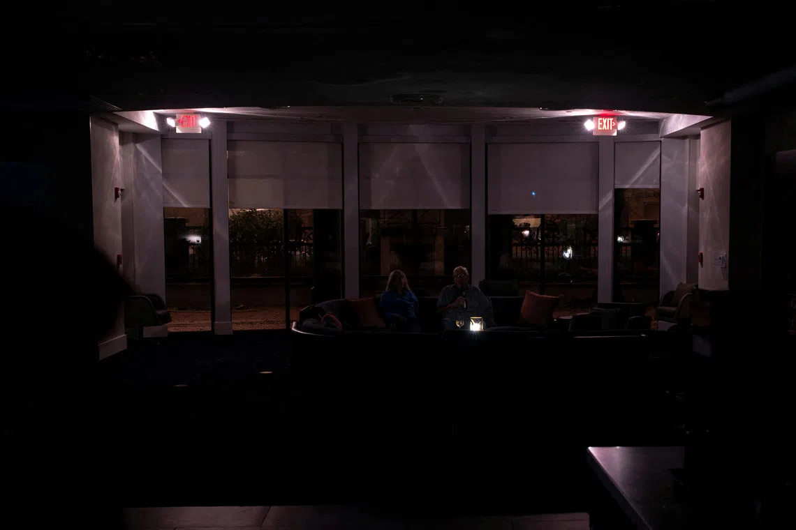 A couple have beers in a hotel lobby during a power outage ahead of the arrival of Hurricane Isaias, in Pensacola, Florida, US, October 9, 2026. REUTERS/Marco Bello