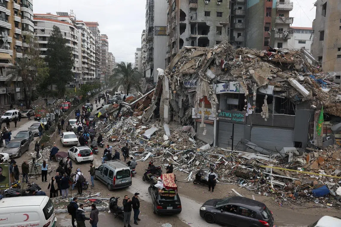 People gather as cars drive past rubble from damaged buildings in Beirut's southern suburbs, after a ceasefire between Israel and Iran-backed group Hezbollah took effect at 0200 GMT on Wednesday after U.S. President Joe Biden said both sides accepted an agreement brokered by the United States and France, in Lebanon, November 27, 2024. REUTERS/Mohamed Azakir      TPX IMAGES OF THE DAY     