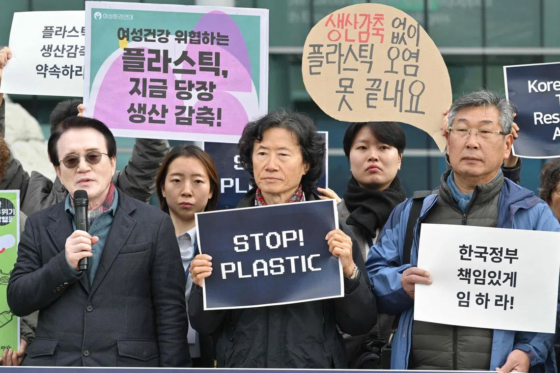 An activist stands with other protesters as he holds a sign that reads “Stop Plastic” in the grounds outside BEXCO, the venue for the fifth session of the UN Intergovernmental Negotiating Committee on Plastic Pollution (INC-5), in Busan on November 25, 2024. (Photo by Anthony WALLACE / AFP)