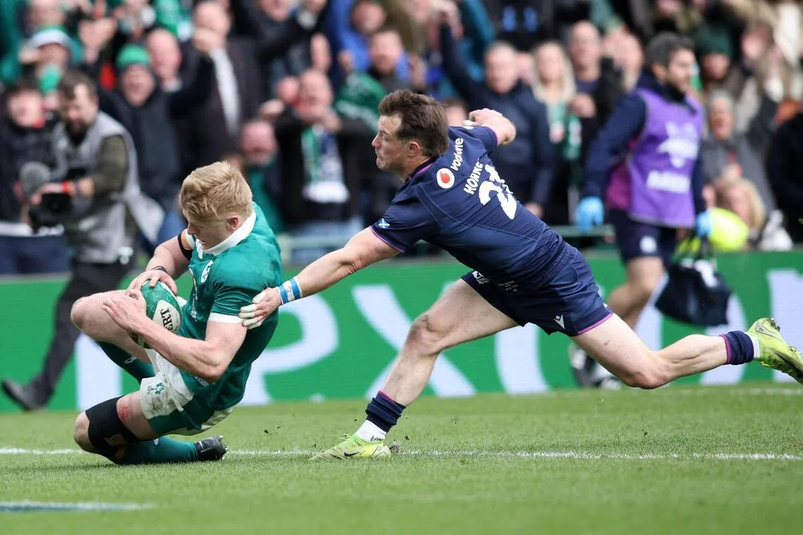 Ireland's wing Tommy O'Brien scores a try despite pressure from Scotland's George Horne in their Six Nations international rugby union match at the Aviva Stadium in Dublin, on March 14, 2026.