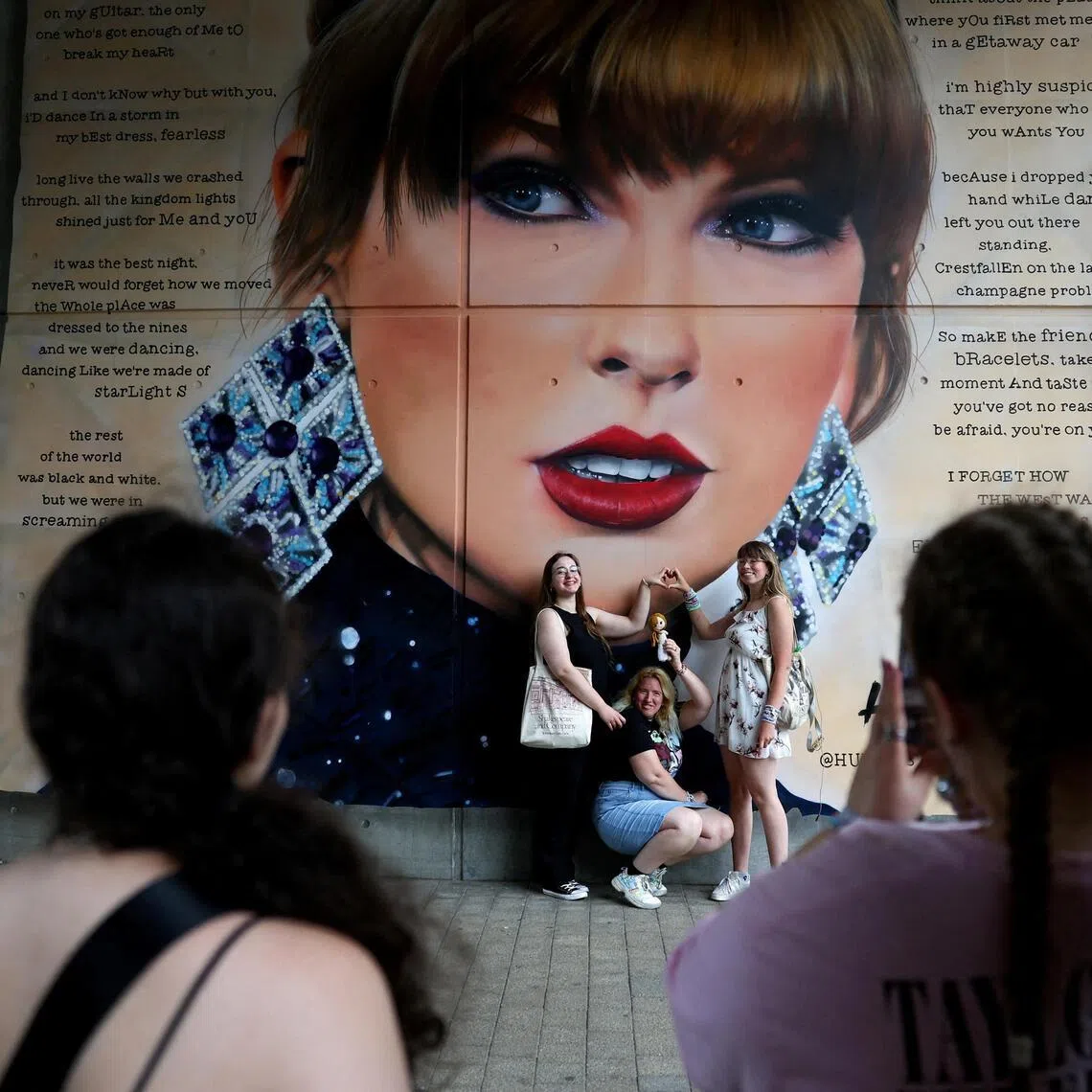 FILE PHOTO: Fans pose next to a Taylor Swift image ahead of her concert, following the cancellation of three Taylor Swift concerts in Vienna because of a planned attack, at Wembley Stadium in London, Britain, August 15, 2024.  REUTERS/Toby Melville/File Photo