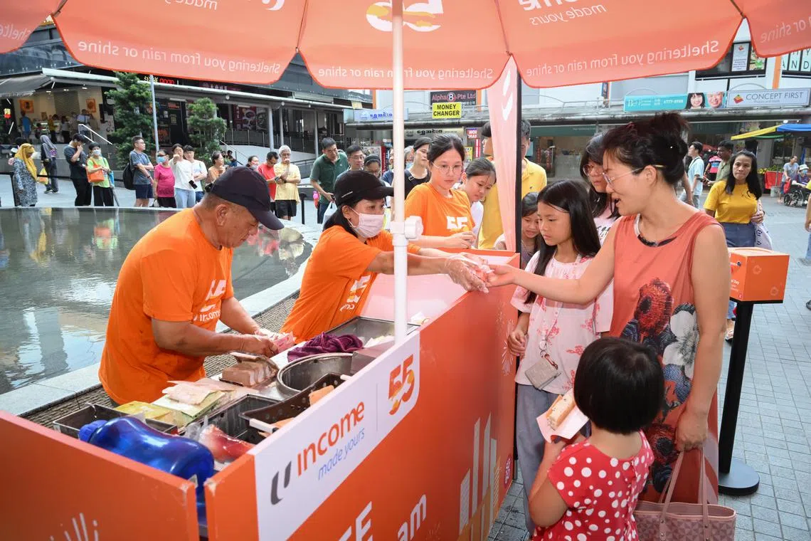 Ice cream vendor Cheong Peng Siong and his assistant Tang Chun Tan serving customer Ren Hui Li and her children near Clementi Mall on Aug 10.