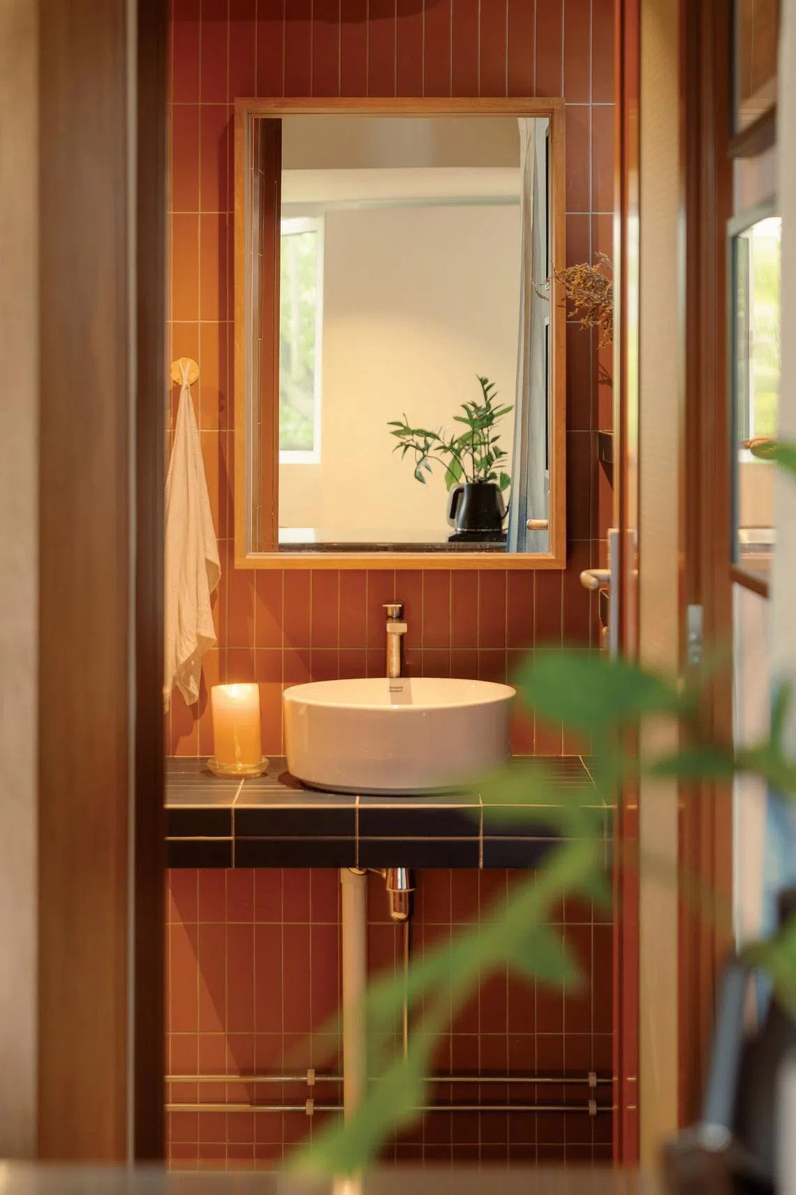 Ladrilhos marrons verticais trazem calor e textura a um banheiro típico. 