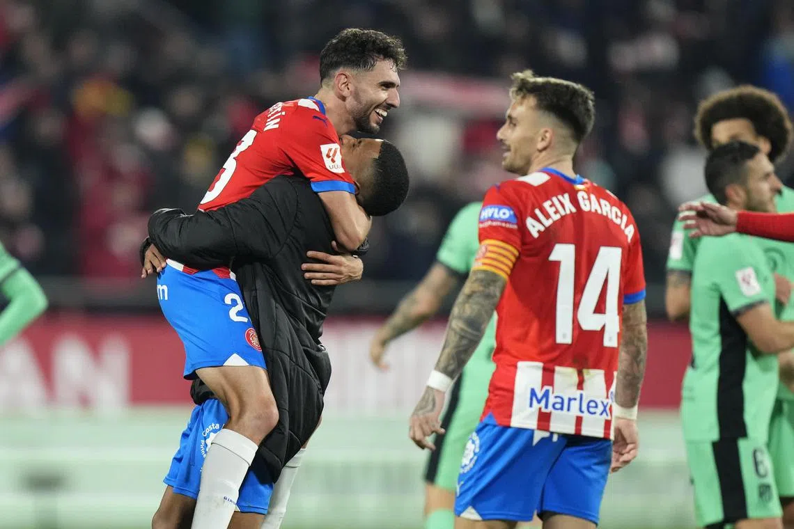 Girona's Ivan Martin is being lifted by a teammate after their win over Atletico Madrid.
