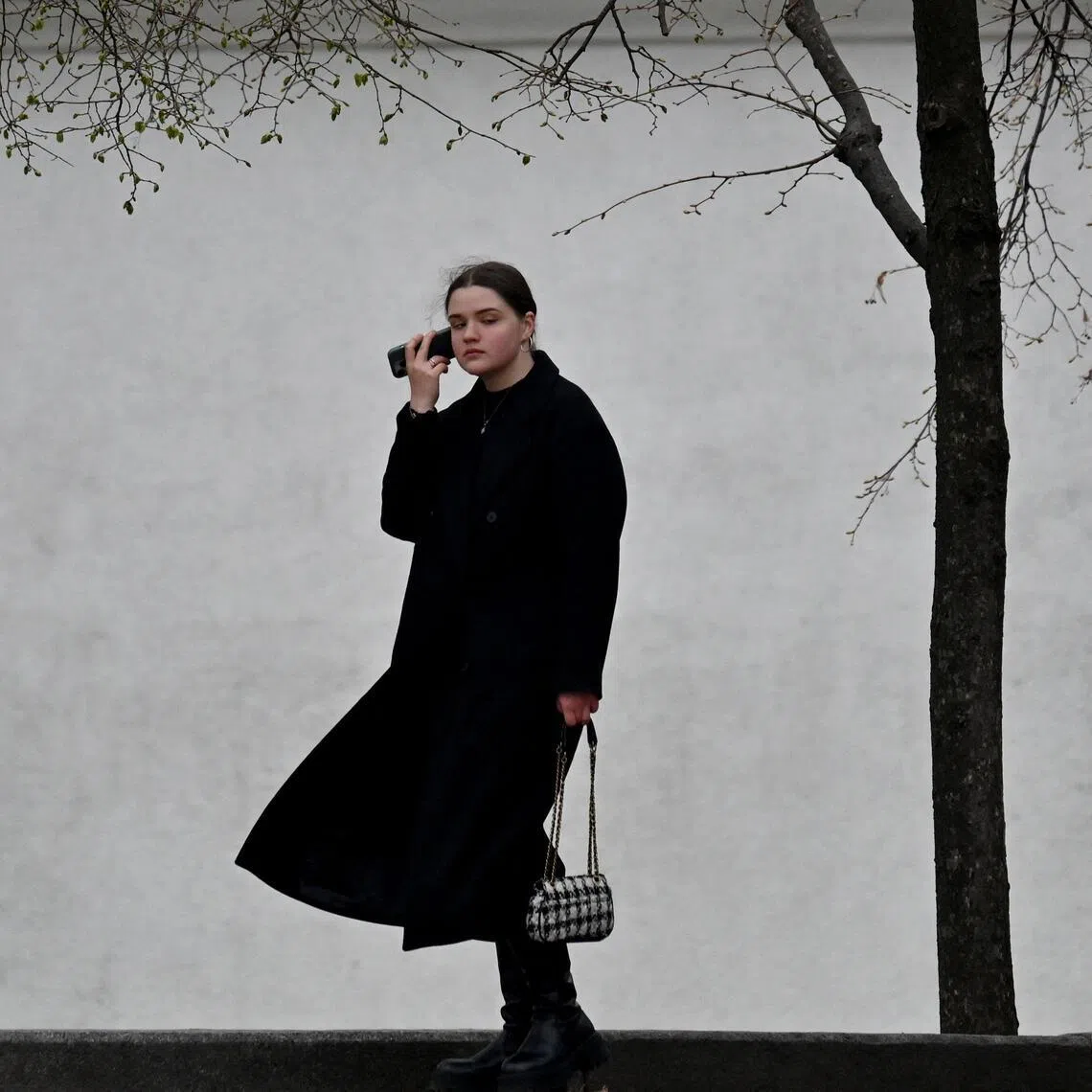 A pedestrian takes a phone call near a placard reading "The Armed Forces of Ukraine are our guardian angels" in Kyiv on April 9, 2026, amid Russian invasion in Ukraine. (Photo by Sergei SUPINSKY / AFP)