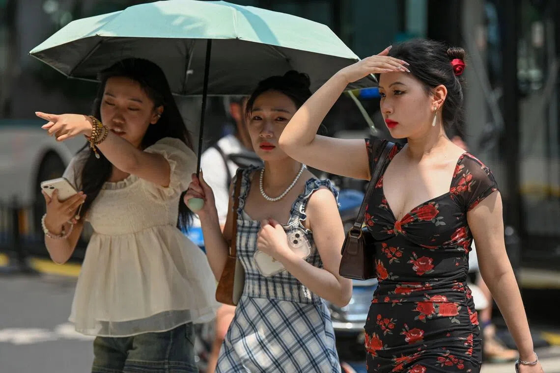 (FILES) Women use an umbrella to shelter from the sun amid hot weather in Shanghai on May 29, 2023. Heatwaves across Asia and beyond have already broken records this year, while the arrival of the El Nino climate phenomenon will mean even more extreme temperatures (Photo by AFP) / China OUT