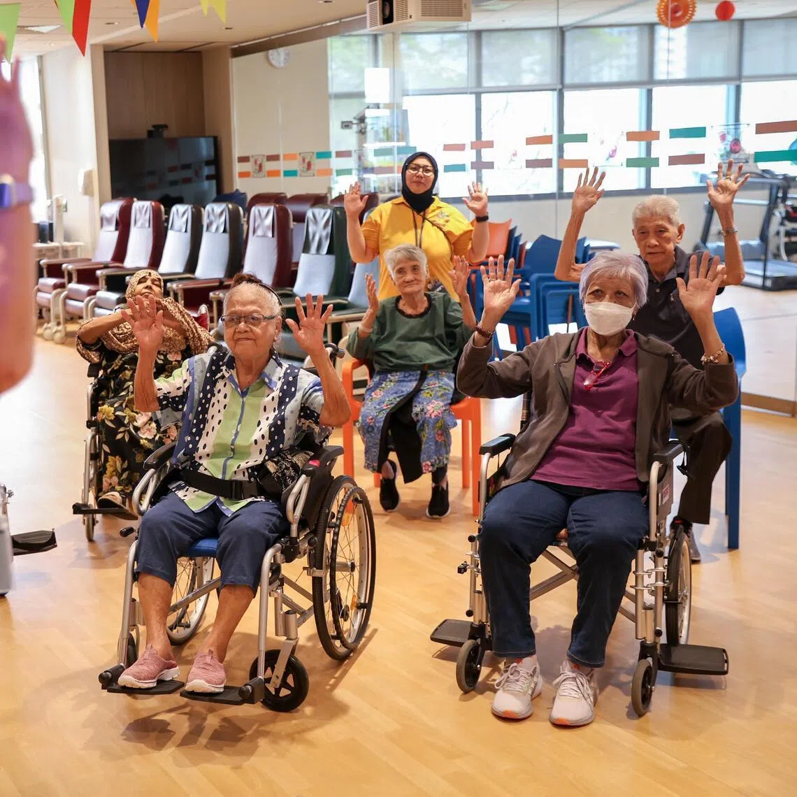 Patients at Dover Park Hospice's day care doing a volunteer-led seated exercise activity.