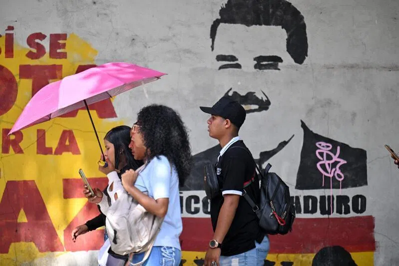 People walk past a mural depicting now ousted Venezuela's President Nicolas Maduro near the National Assembly in Caracas on Jan 5, 2026.