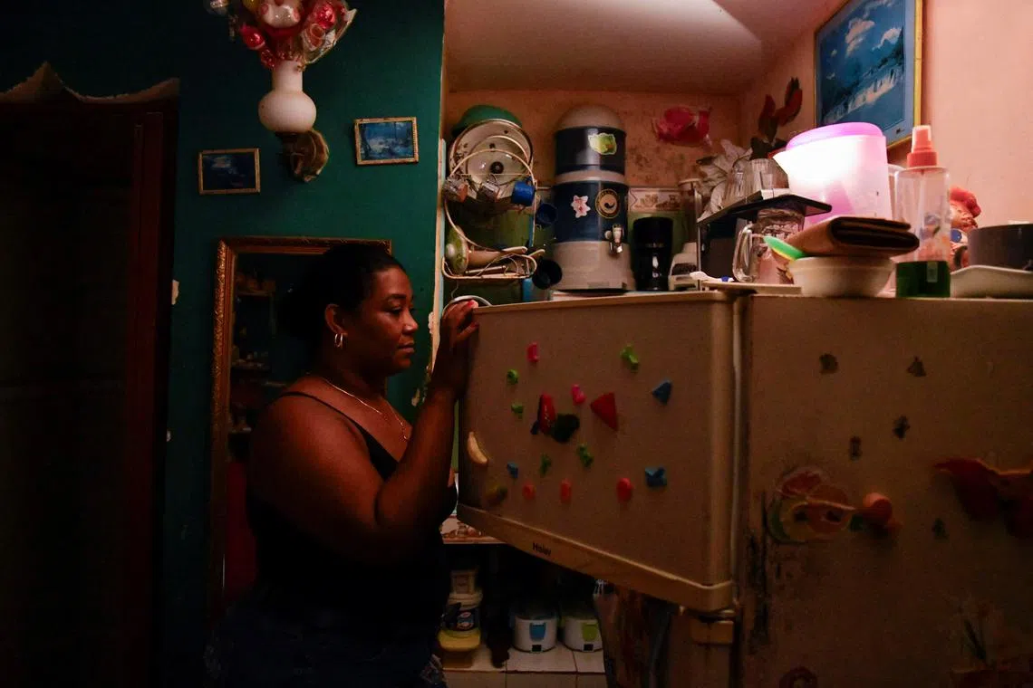 Ramona Miranda opens a refrigerator with the aid of a cell phone light as Cuba is hit by an island-wide blackout, in Havana, Cuba, October 18, 2024. REUTERS/Norlys Perez