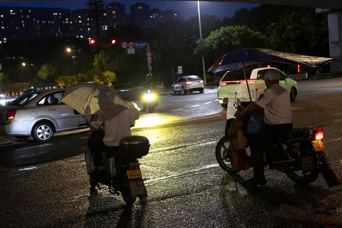 Commuters sheltering while riding their motorbikes in the rain ahead of Typhoon Bavi’s landfall, in Wenzhou, Zhejiang province, eastern China, on July 11.