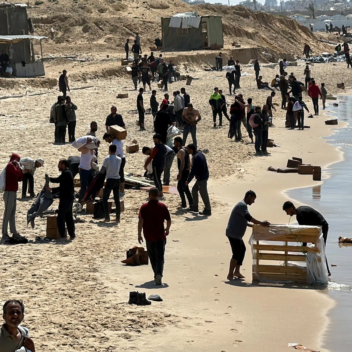 Palestinians gather on a beach as they collect aid airdropped by an airplane, amid the ongoing conflict between Israel and Hamas.