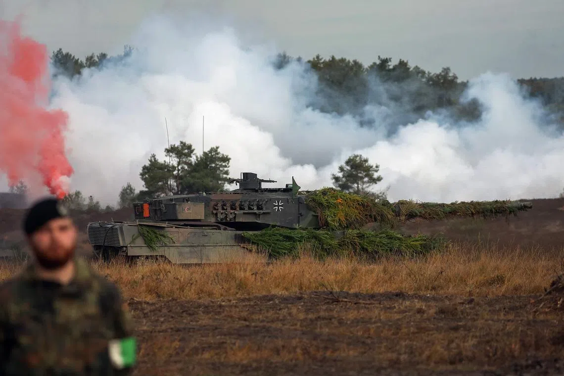 A soldier stands next to a Leopard 2 battle tanks of the German armed forces during a training exercise in Ostenholz, northern Germany, on Oct 17, 2022.