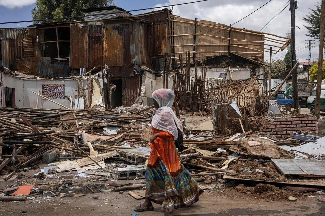 A woman walking past debris from houses during a planned demolition in the historical Piazza neighbourhood of Addis Ababa on March 14, 2024. 