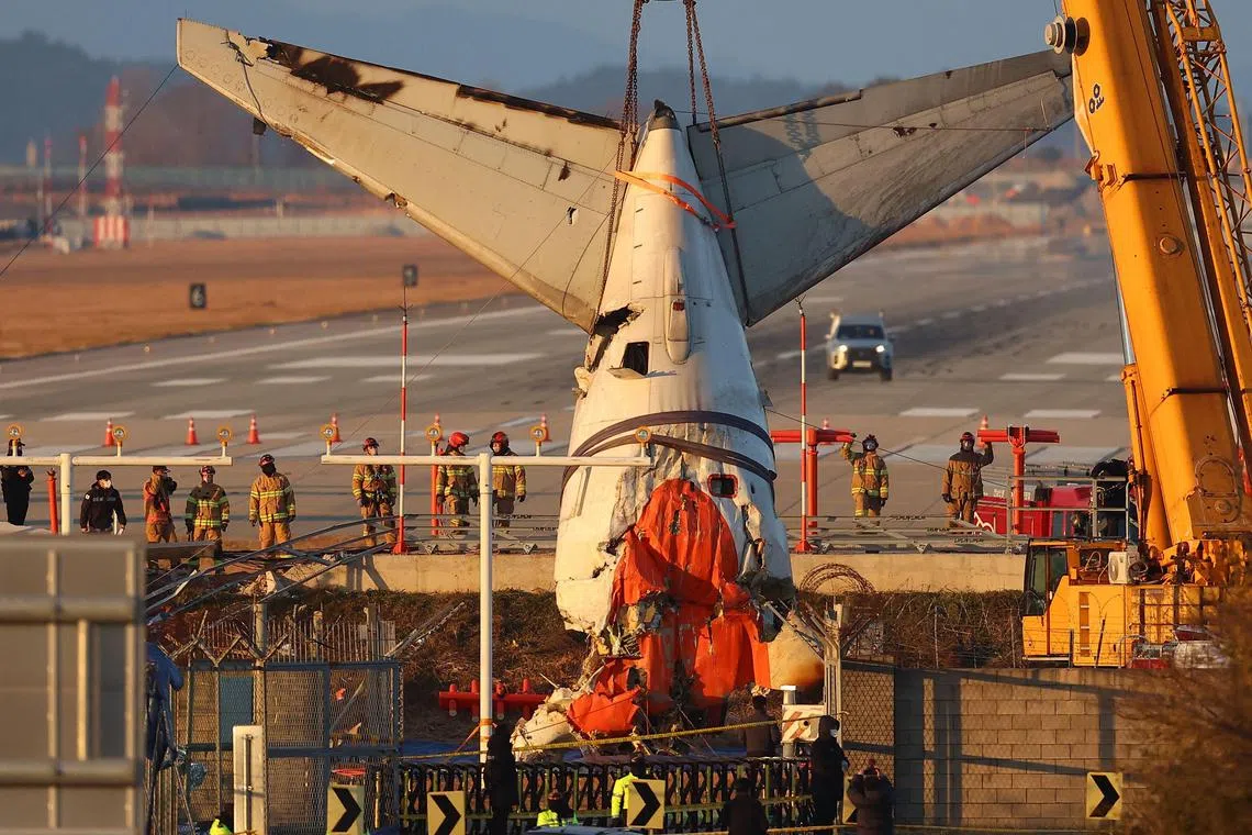 TOPSHOT - A crane lifts the tail section during the salvage operation of the Jeju Air Boeing 737-800 aircraft which crashed and burst into flames at Muan International Airport, in Muan on January 3, 2025. Jeju Air flight 2216 was carrying 181 people from Thailand to South Korea on December 29, 2024, when it issued a mayday call and belly-landed before hitting a barrier and bursting into flames, killing everyone aboard except two flight attendants pulled from the burning wreckage. (Photo by YONHAP / AFP) / South Korea OUT / NO ARCHIVES -  RESTRICTED TO SUBSCRIPTION USE