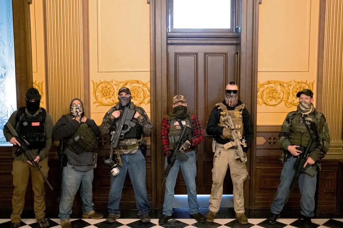 A Michigan militia group, including  (from far right) Pete Musico, Paul Bellar and Joseph Morrison, stands in front of the governor's office, after protesters occupied the state capitol building in April 2020.