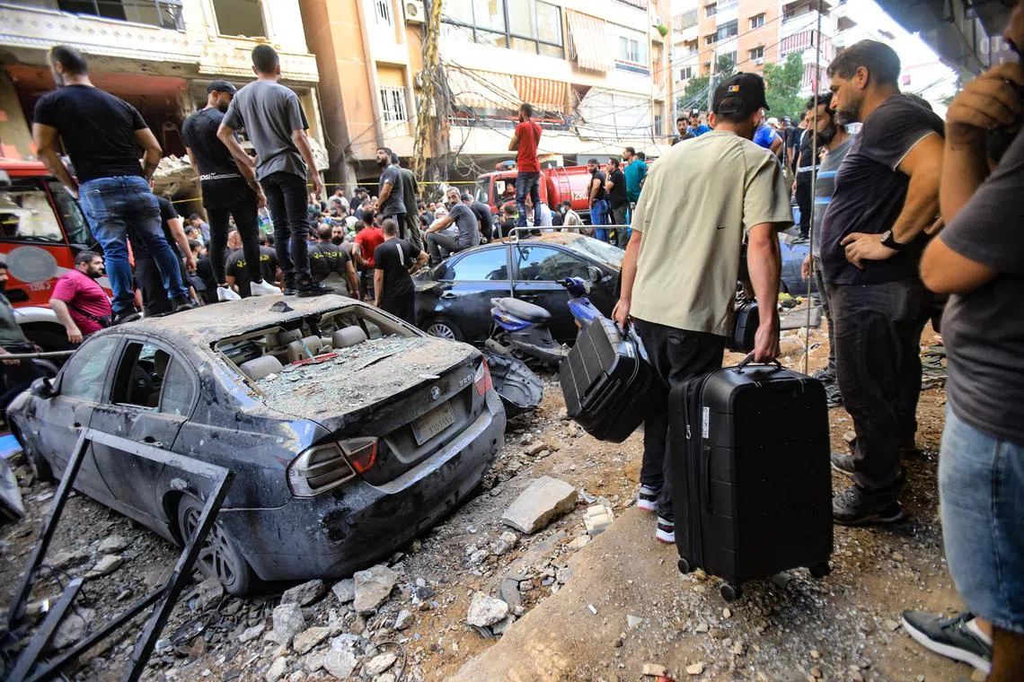 People gather in front of a building targeted by an Israeli strike in Beirut's southern suburbs, on Sept 20.