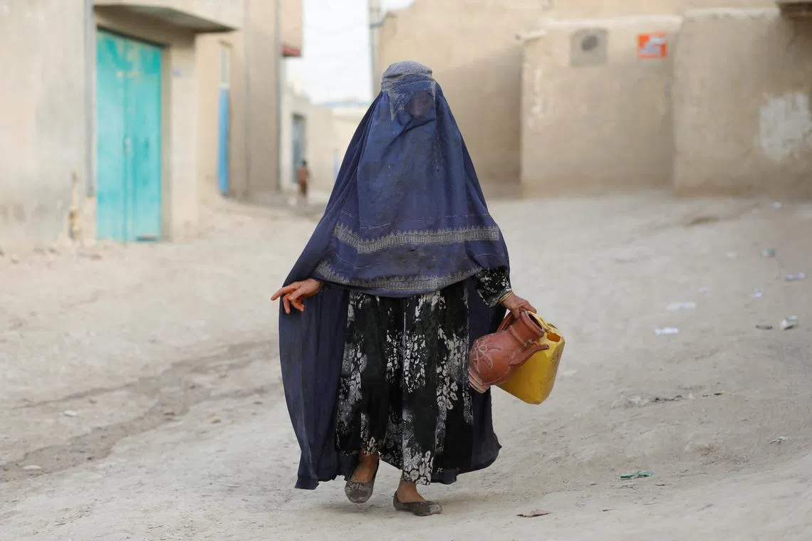 File photo: An Afghan woman carries empty containers to fetch water in Nahr-e-Shahi district in Balkh province, Afghanistan, August 6, 2023. REUTERS/Ali Khara/File photo