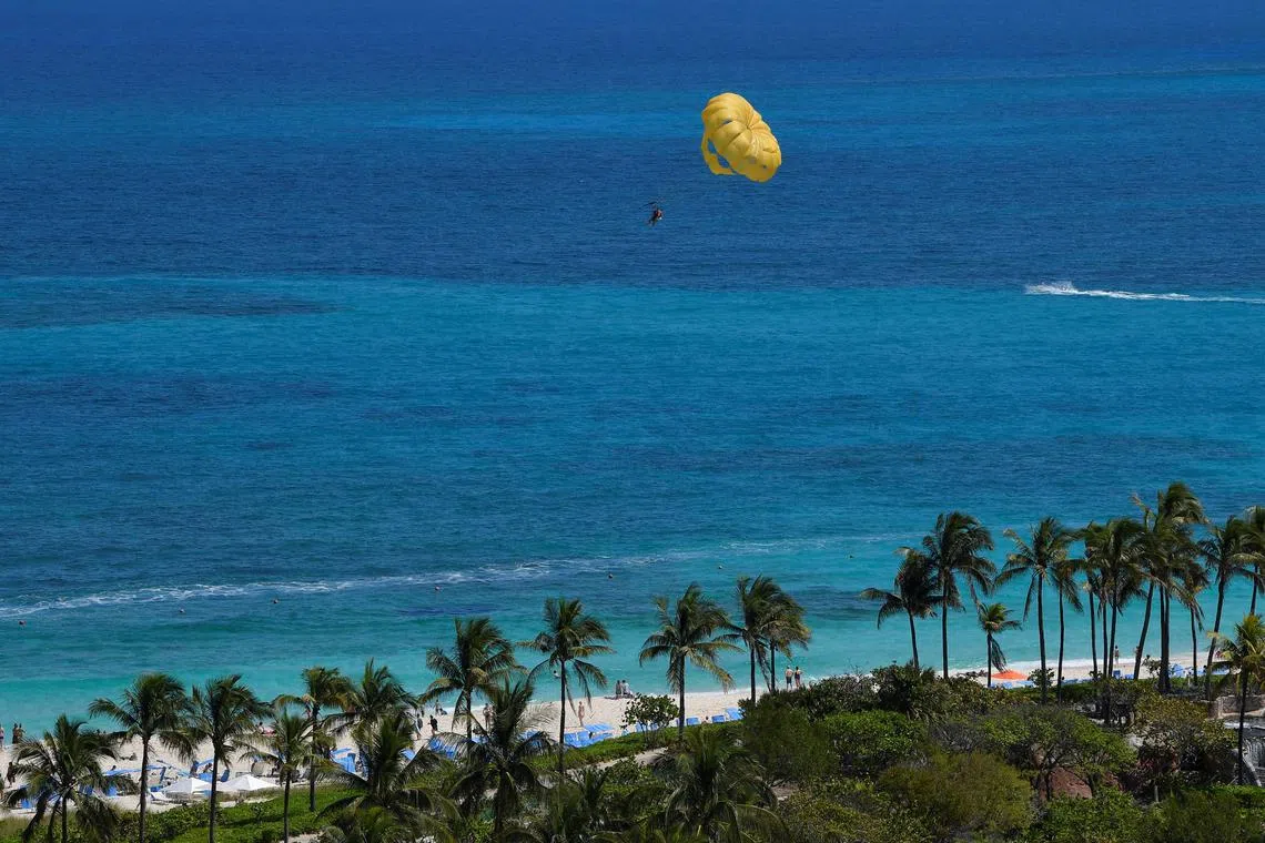 FILE PHOTO: Holidaymakers attached to a parachute are pulled by a speedboat along the coastline in Nassau, Bahamas, March 26, 2022.  REUTERS/Toby Melville/File Photo