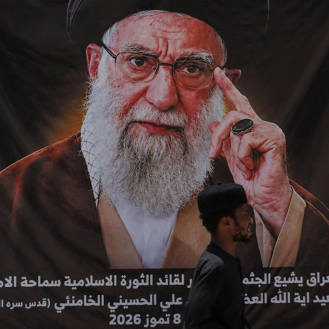 A man walks past a banner bearing a portrait of Iran's late Supreme Leader Ayatollah Ali Khamenei ahead of funeral processions in Najaf and Karbala, in Najaf, Iraq, July 7, 2026. REUTERS/Thaier Al-Sudani