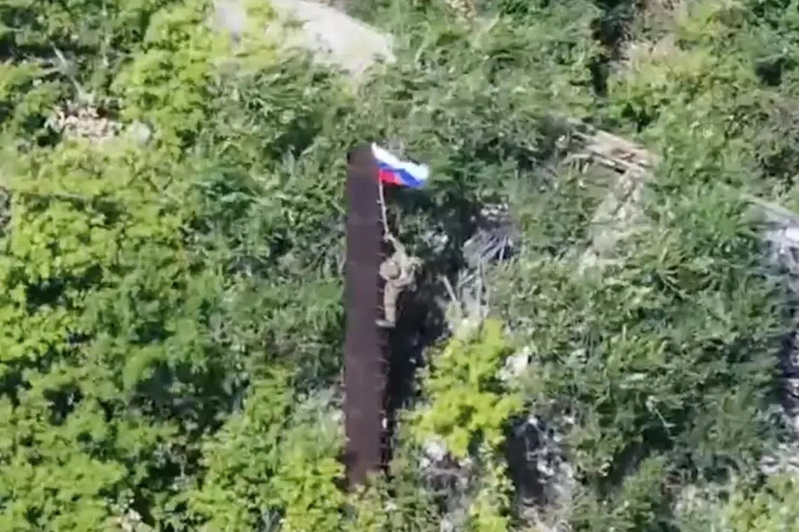 A still image, taken from footage released by the Russian Defence Ministry, shows what it said to be a Russian soldier raising a flag following the capture of Ukraine's Yablunivka (Yablonovka) settlement in the Donetsk region in the course of Russia-Ukraine military conflict, in this image from video released August 12, 2025. Russian Defence Ministry/Handout via REUTERS