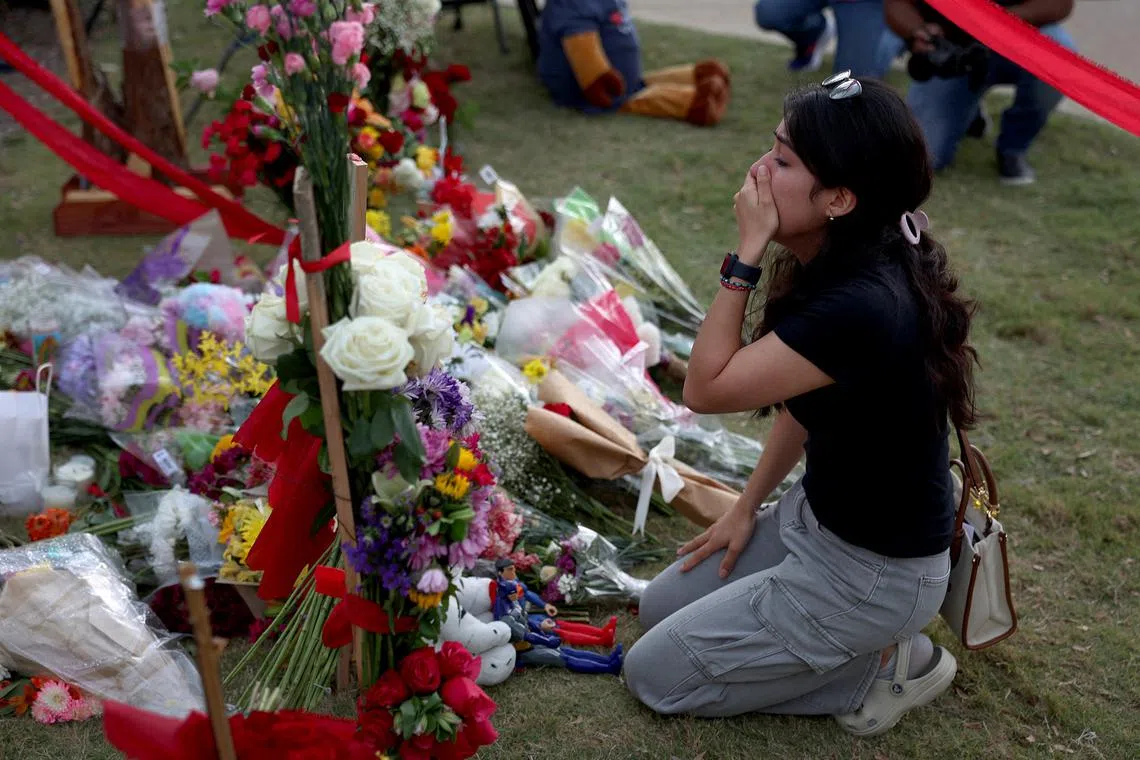 A woman reacts as she visits a memorial setup near an entrance to the Allen Premium Outlets mall after the mass shooting.