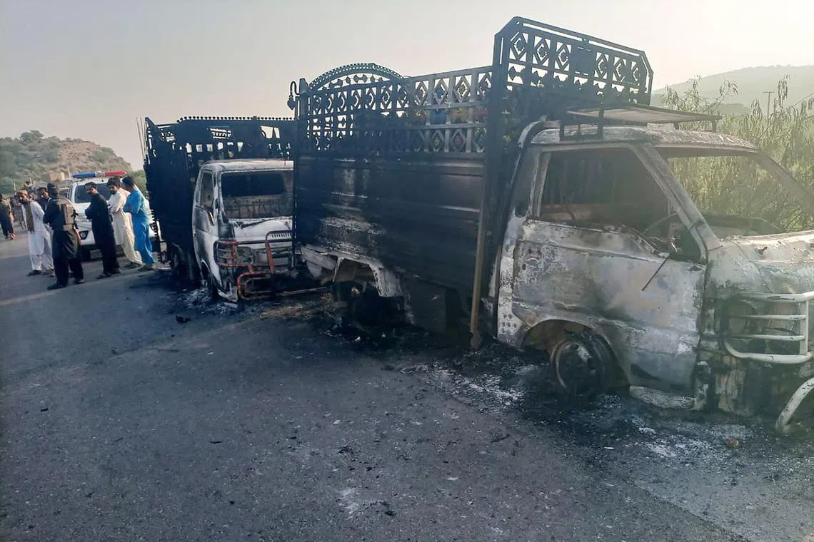 Security personnel stand near the charred vehicles at the shooting site on the national highway in Musakhail district, Balochistan province .