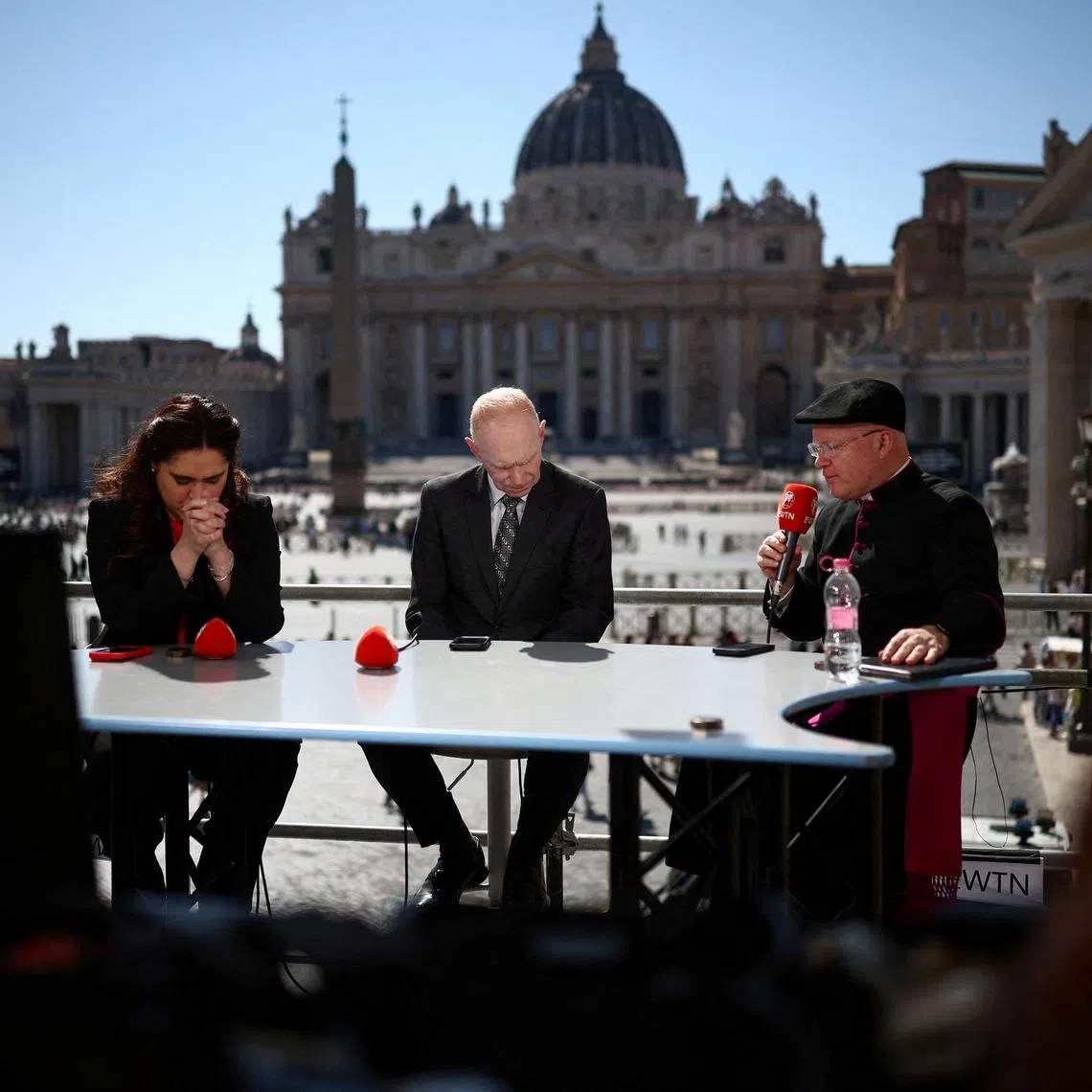 Montse Alvarado, President and COO of EWTN News (Eternal Word Television Network) a U.S.-based media bringing news to Catholics worldwide, Matthew Bunson, Vice President of EWTN, and Monsignor Roger Landry pray during a live broadcast near St.Peter's square at the Vatican, in Rome, Italy, May 1, 2025. REUTERS/Guglielmo Mangiapane