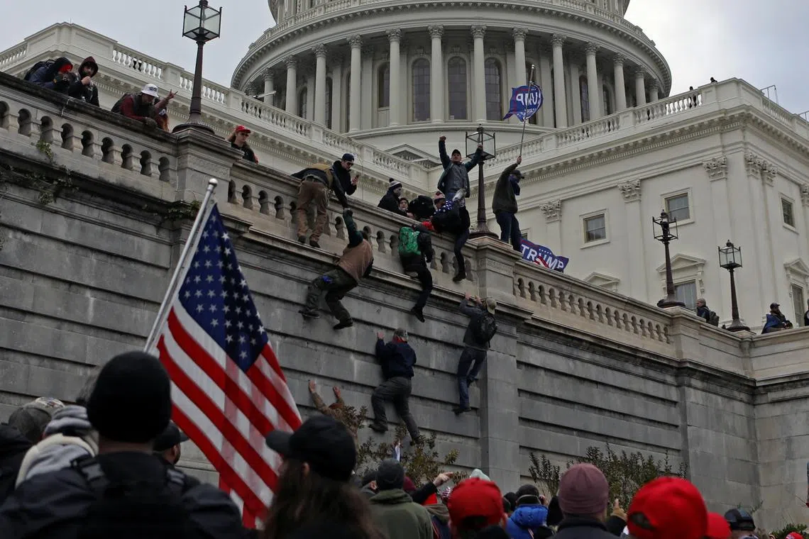 FILE PHOTO: Supporters of U.S. President Donald Trump climb a wall during a protest against the certification of the 2020 presidential election results by the Congress, at the Capitol in Washington, U.S., January 6, 2021. Picture taken January 6, 2021. REUTERS/Jim Urquhart/File Photo