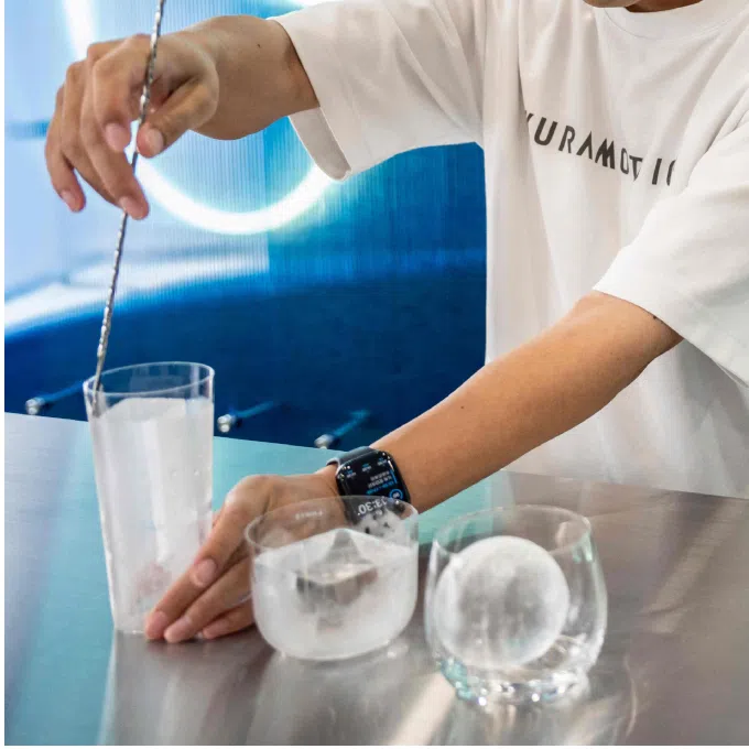 (Left) Fifth-generation owner Kazuhiko Kuramoto stirring ice at the Kuramoto Ice factory in Kanazawa, Japan. (Right) A negroni cocktail with Kuramoto Ice at a bar in Hilton Narita in Chiba prefecture.