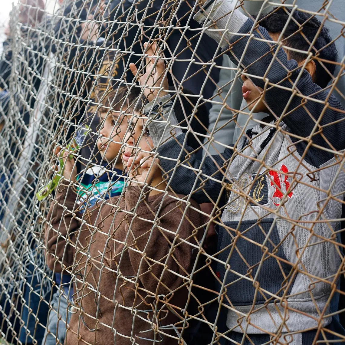 Palestinians watch, as people play football on a pitch in Gaza City.