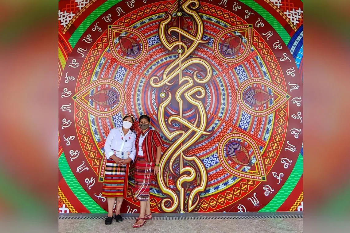 Two women pose in front of the Baybayin-inspired mural created in Baguio City by calligrapher Taipan Lucero, known for combining elements of the Philippine ancient script and traditional Filipino culture in his artworks he call "CalligraFilipino".