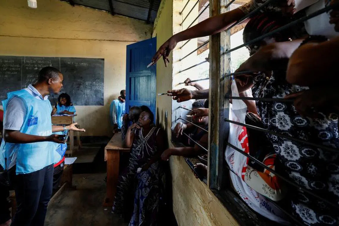 An election official checks the identity cards of people who are waiting to vote in the Democratic Republic of Congo's parliamentary and presidential election after authorities extended opening hours for polling stations that failed to open the previous day, in Kinshasa, the Democratic Republic of Congo December 21, 2023. REUTERS/Zohra Bensemra/File Photo