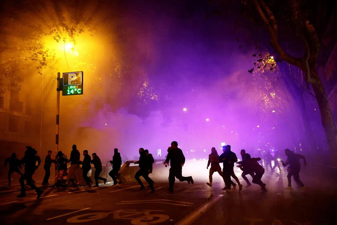 Demonstrators running next to riot police during a protest near Spain's Socialists Party headquarters in Madrid, Spain, on Nov 11, 2023. 