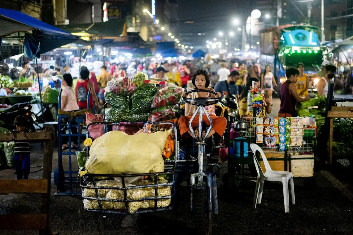 A child sits in a motorized vehicle loaded with vegetables at a public market in Manila, Philippines, October 21, 2022. REUTERS/Lisa Marie David