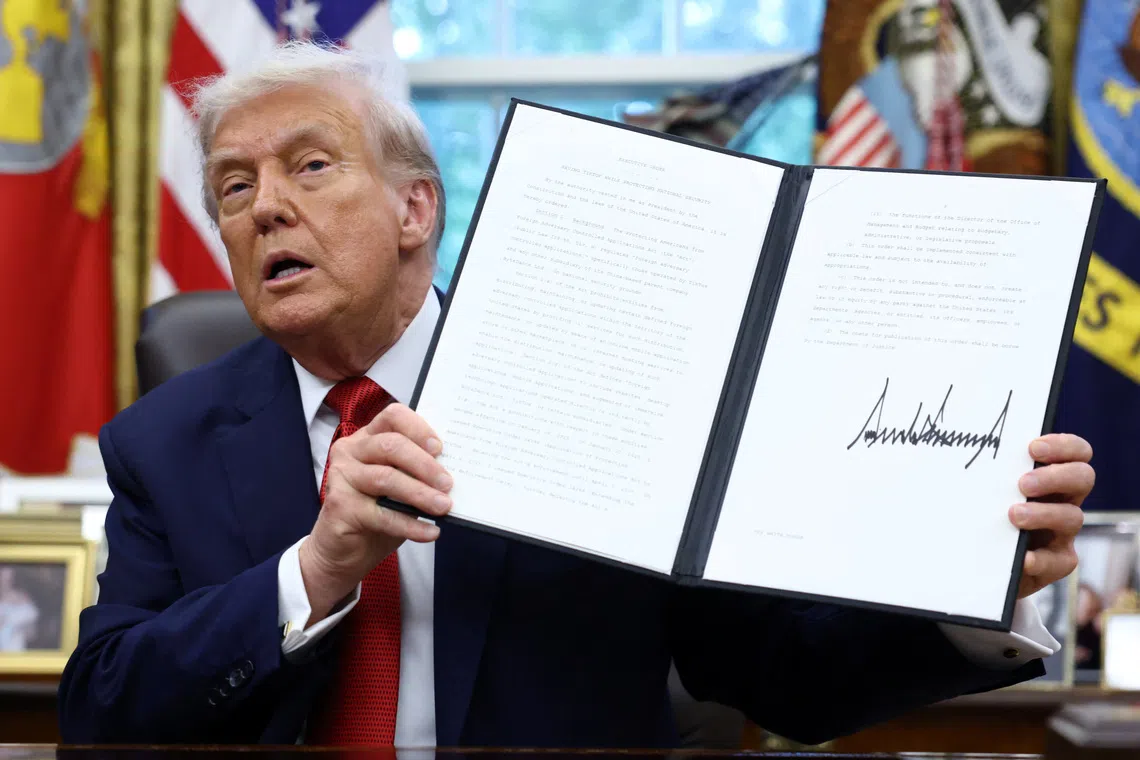 U.S. President Donald Trump shows a signed executive order on a deal that would divest TikTok's U.S. operations from ByteDance from its Chinese owner ByteDance, at the White House in Washington, D.C., U.S., September 25, 2025. REUTERS/Kevin Lamarque