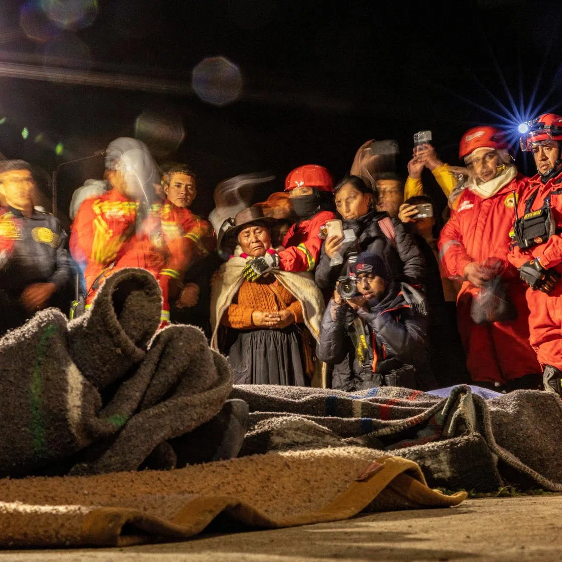 People in Chupuro, Peru, on July 19 praying next to the bodies of four victims of an earthquake that struck the centre of the country a day ago.