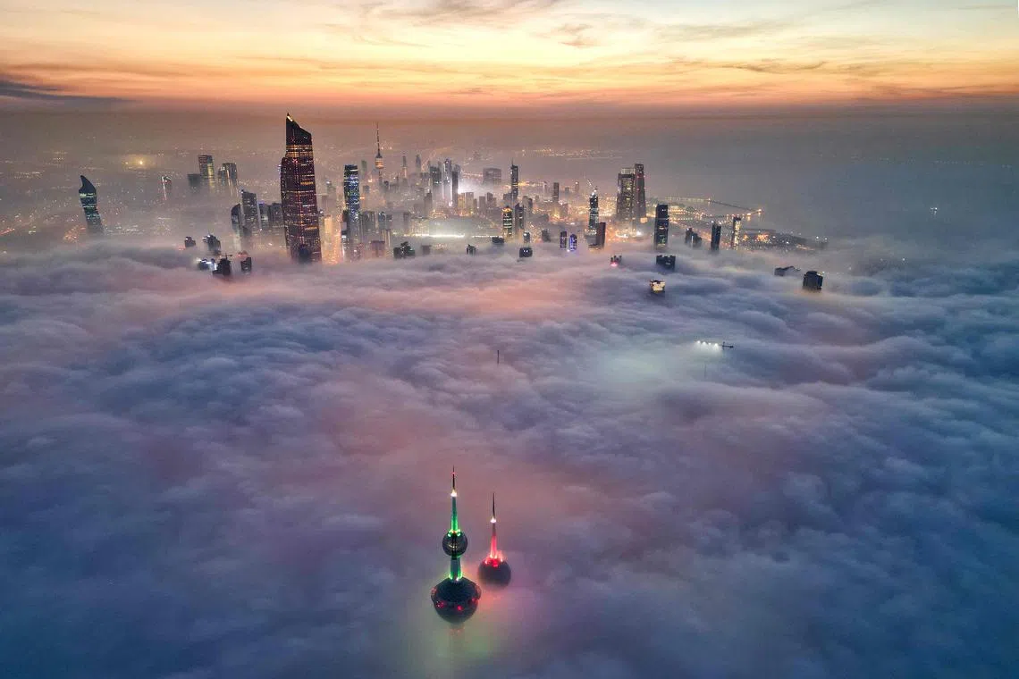 In this aerial view, the landmark Kuwait Towers and other skyscrapers pierce through the cloud cover over Kuwait City on Dec 10.