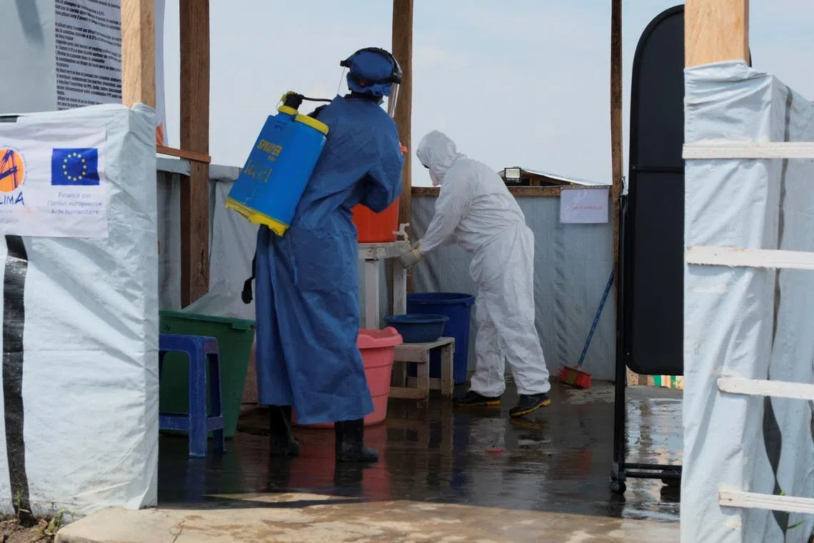 Medical workers dressed in personal protective equipment (PPE) disinfect and wash their hands at an Ebola treatment centre during a ceremony to present recovery certificates to patients at the Rwambara General Reference Hospital in Bunia, eastern Democratic Republic of Congo, June 16, 2026. REUTERS/Gradel Muyisa Mumbere