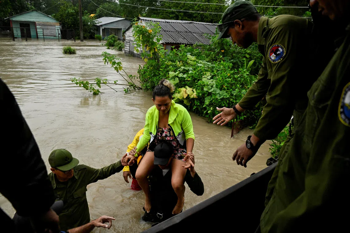 A woman is evacuated from her home by emergency personnel after the Cauto River flooded due to Hurricane Melissa, in Rio Cauto, Granma Province, Cuba October 31, 2025. REUTERS/Norlys Perez