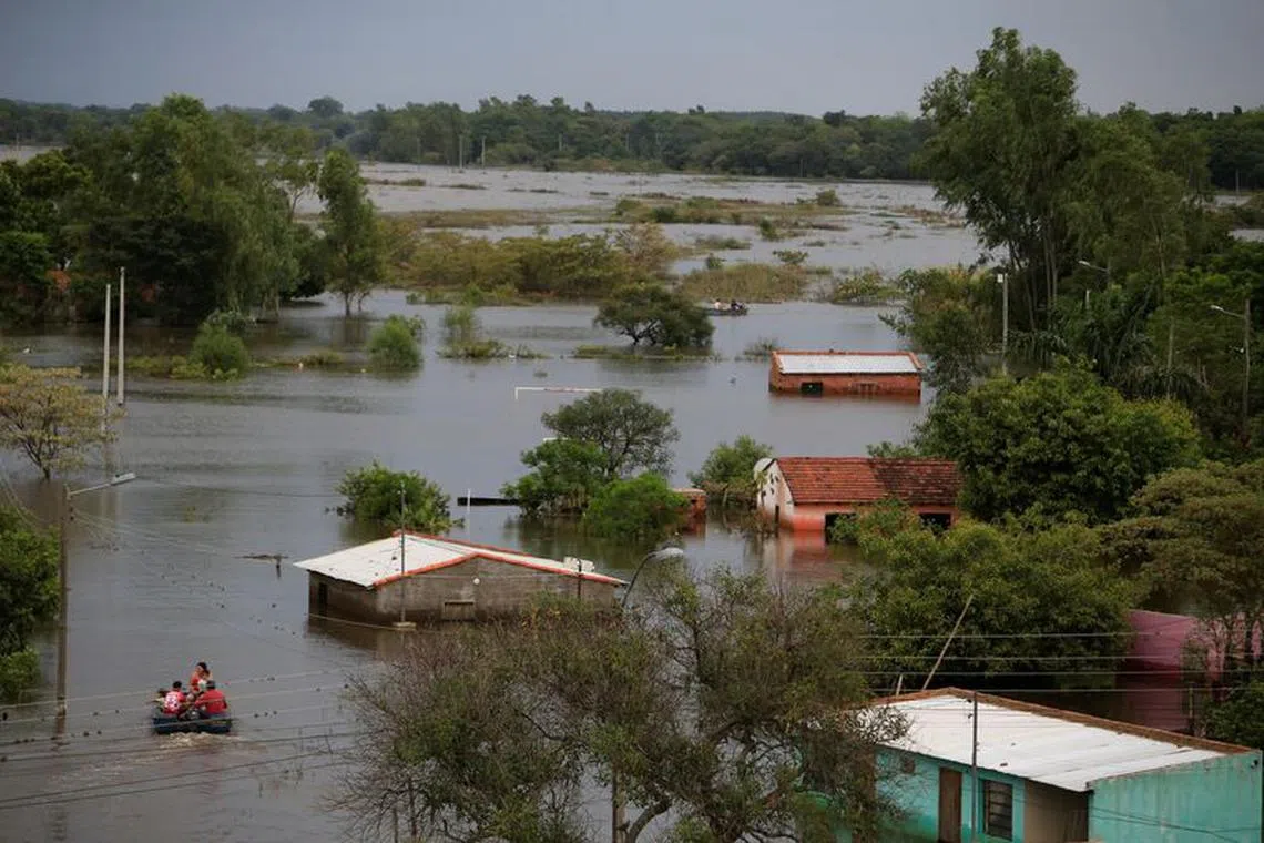 People ride in a boat in a flooded area after the Parana river overflowed its banks due to heavy rain upstream, in Ayolas, Paraguay November 8, 2023. REUTERS/Cesar Olmedo