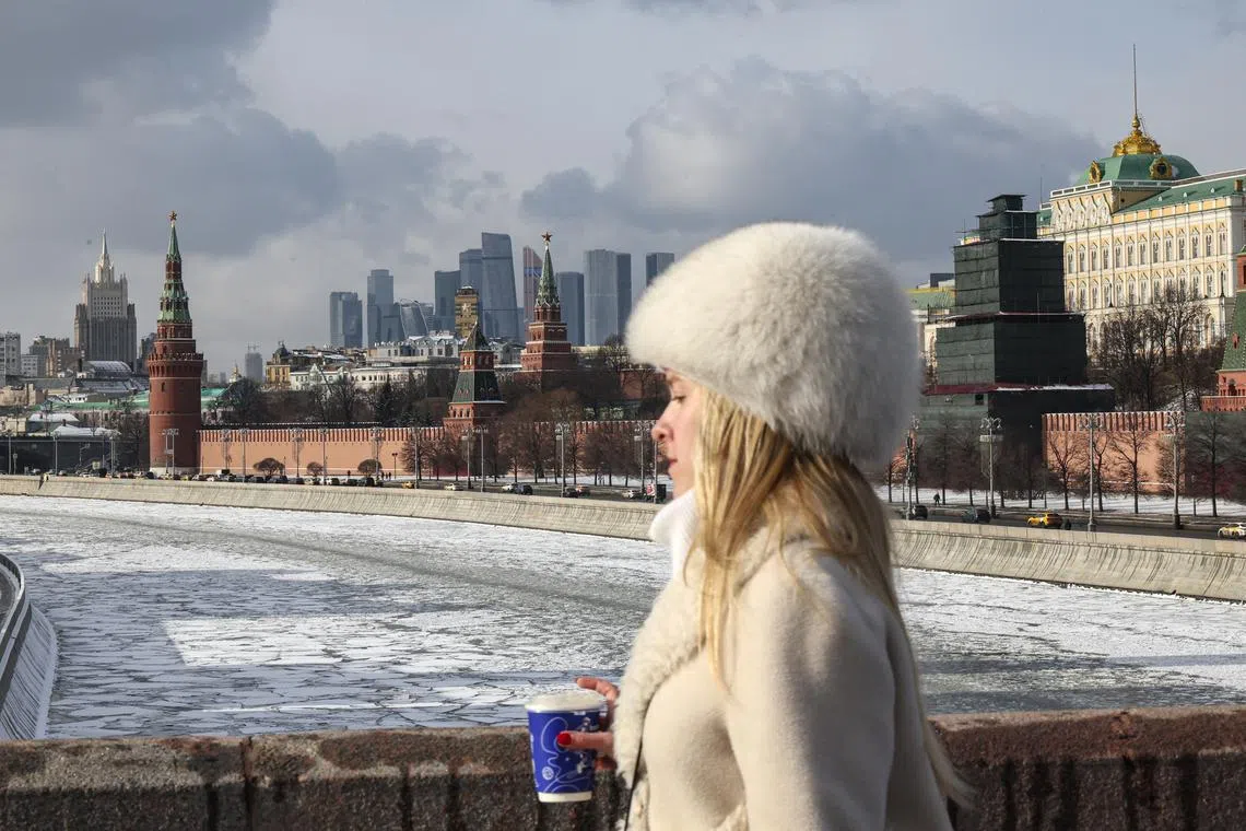 A woman walking on a bridge over the frozen Moskva river in front of the Kremlin in Moscow, Russia, on Feb 19, 2025. 