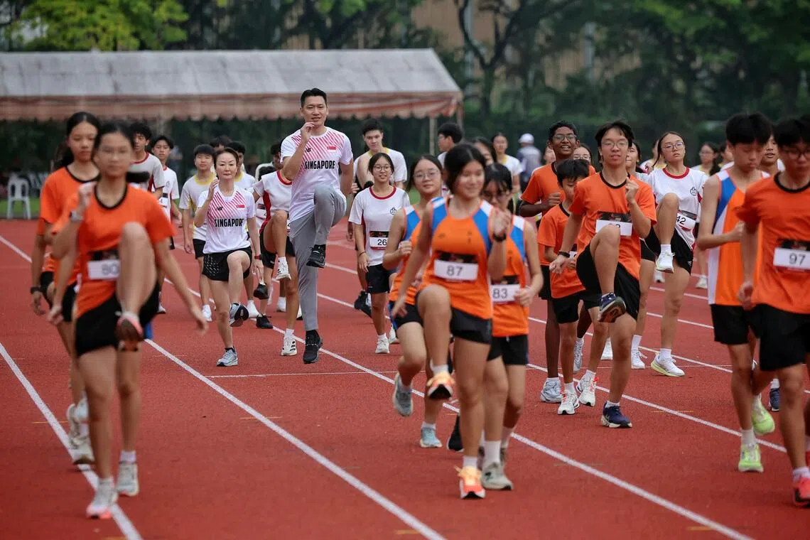 Minister for Culture, Community and Youth David Neo (centre) joining students for a warm-up ahead of the competition at the West Zone Athletics Meet at Hwa Chong Institution on Oct 26.