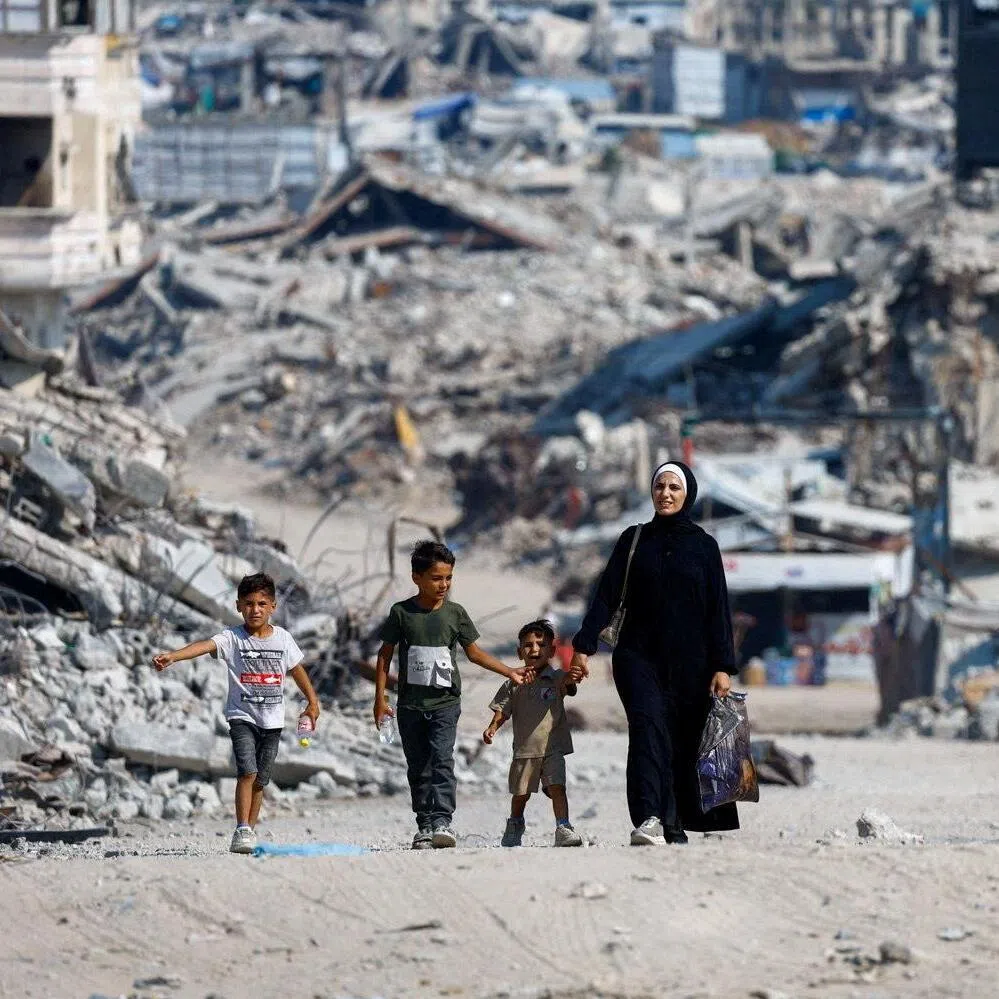 Palestinians walking past the rubble of residential buildings destroyed during the war, in Gaza City, on Aug 15.