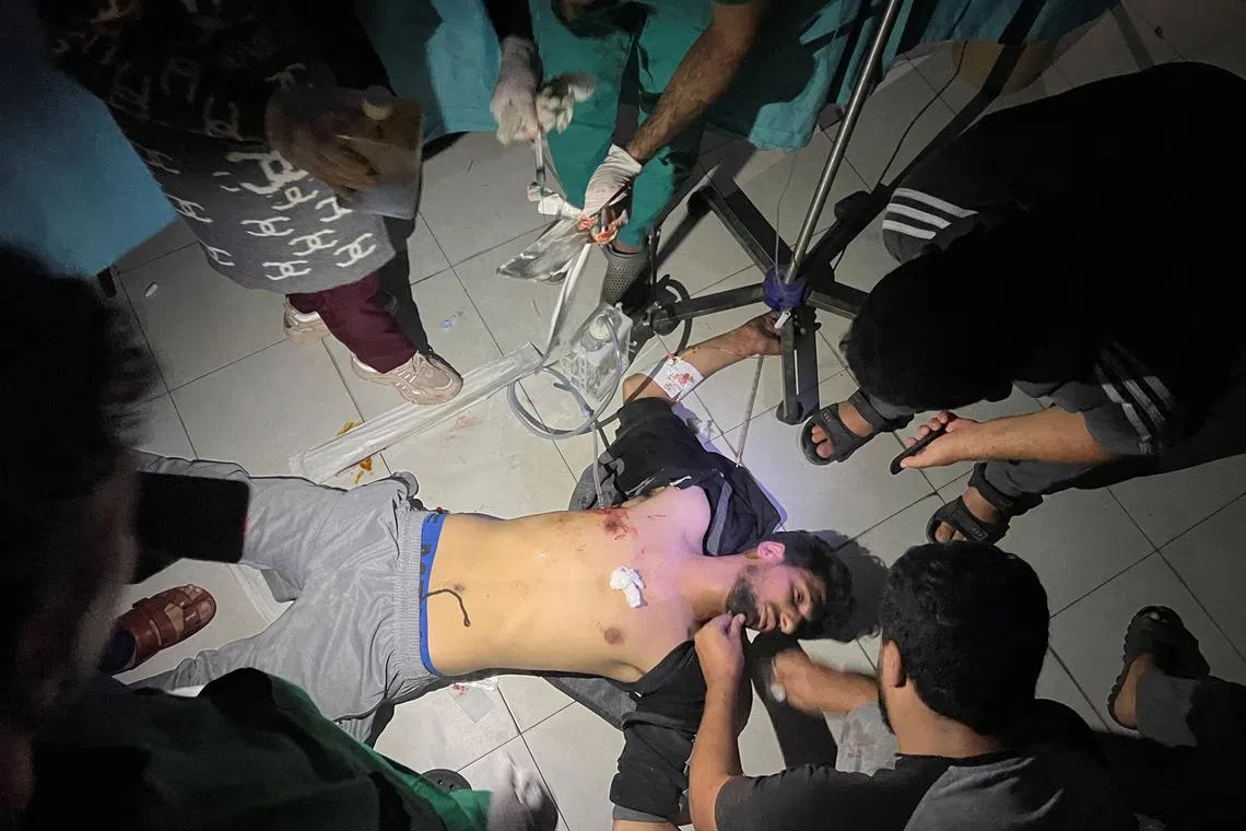 Medical staff at the Indonesian hospital use phone flashlights to help a Palestinian man wounded in Israeli strikes, after Gaza's Al-Shifa hospital went out of service.