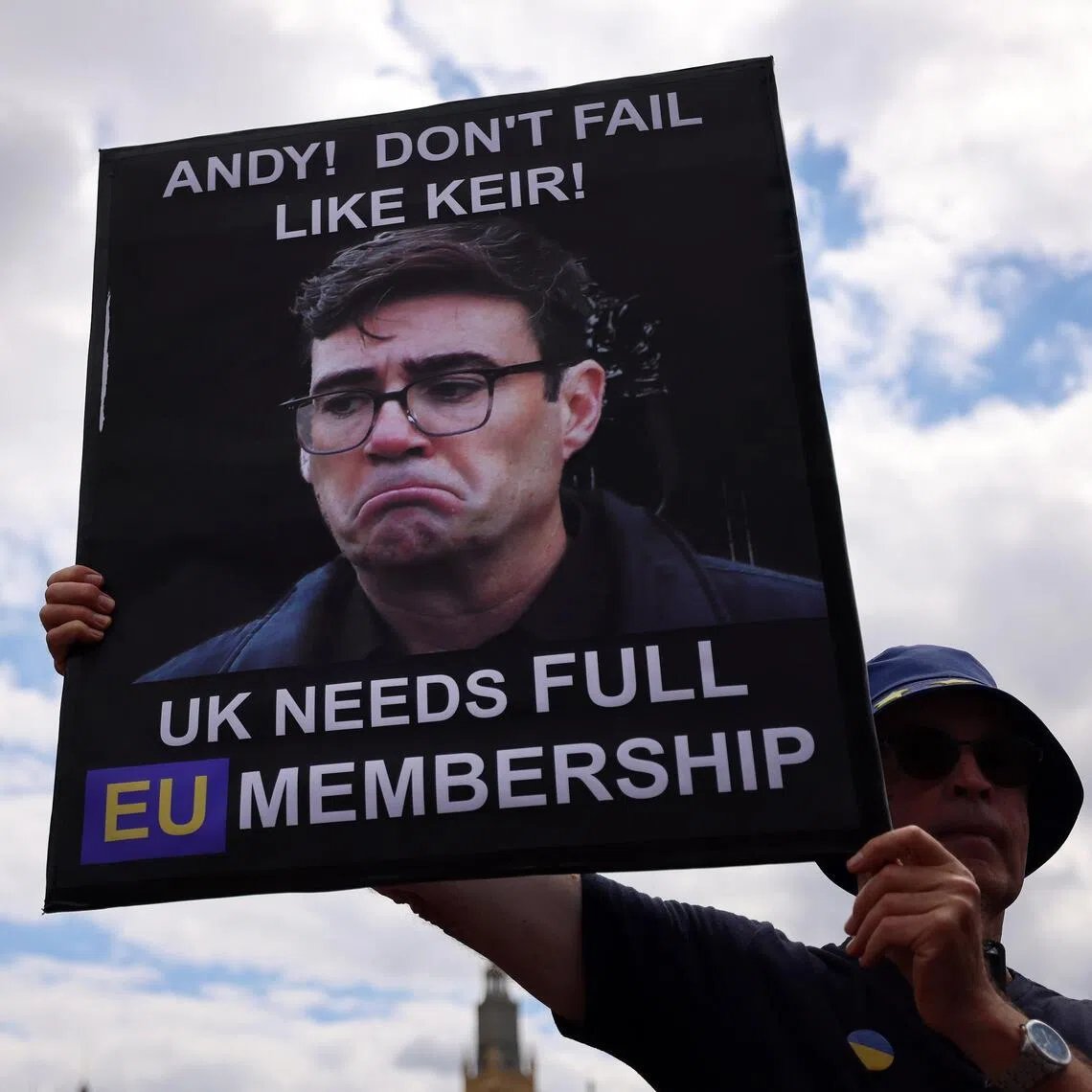 epa13077590 A pro-EU campaigner holds up a sign of Andy Burnham outside Parliament in London, Britain, 01 July 2026. Pro-EU campaigners are hoping prime minister-in-waiting Andy Burnham will seek closer ties to the EU. EPA/ANDY RAIN