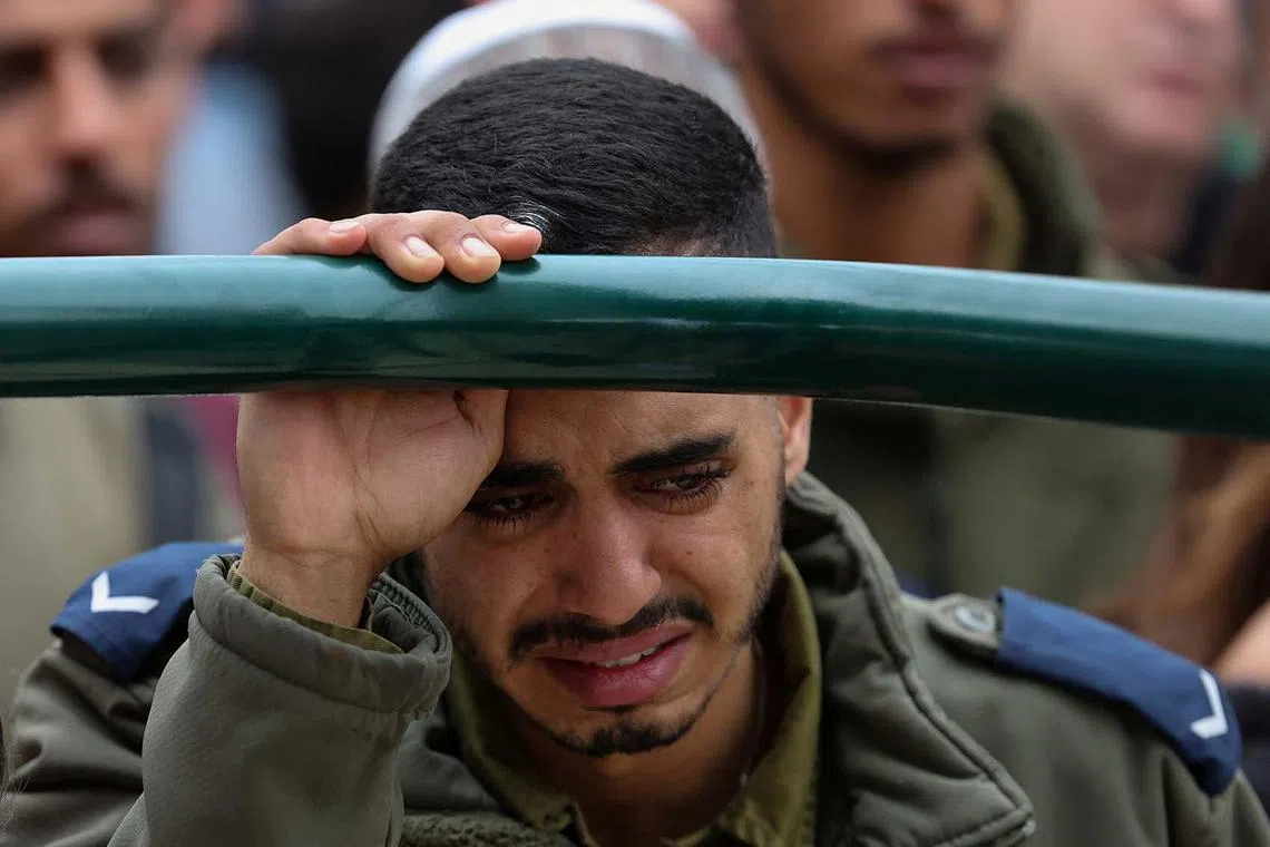 An Israeli soldier reacts, as friends and family mourn Israeli soldier Sergeant Lavi Ghasi, 19, who was killed in northern Gaza during the ongoing ground operation by Israel's military in the Gaza Strip, at his funeral in Modiin, Israel, Dec 21, 2023. 