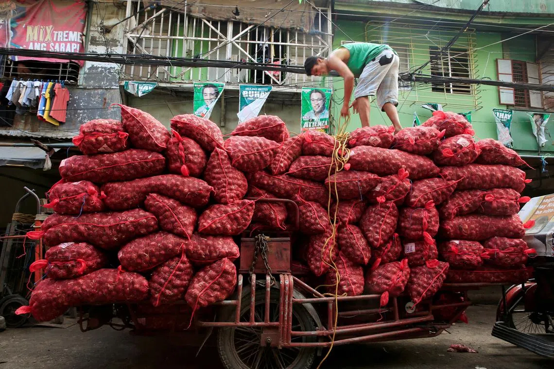 A worker stands on top of piles of red onion sacks in Metro Manila on July 4, 2016.