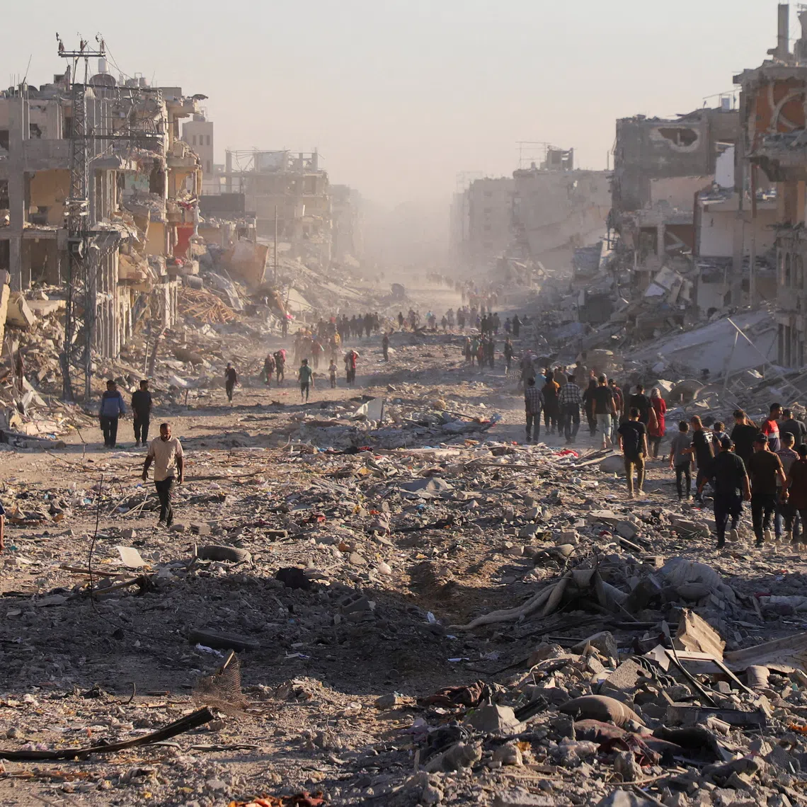 Palestinians walk through a damaged neighborhood in the aftermath of an Israeli operation, after Israel's government ratified a ceasefire with Hamas, in Gaza City, October 10. REUTERS/ Ebrahim Hajjaj